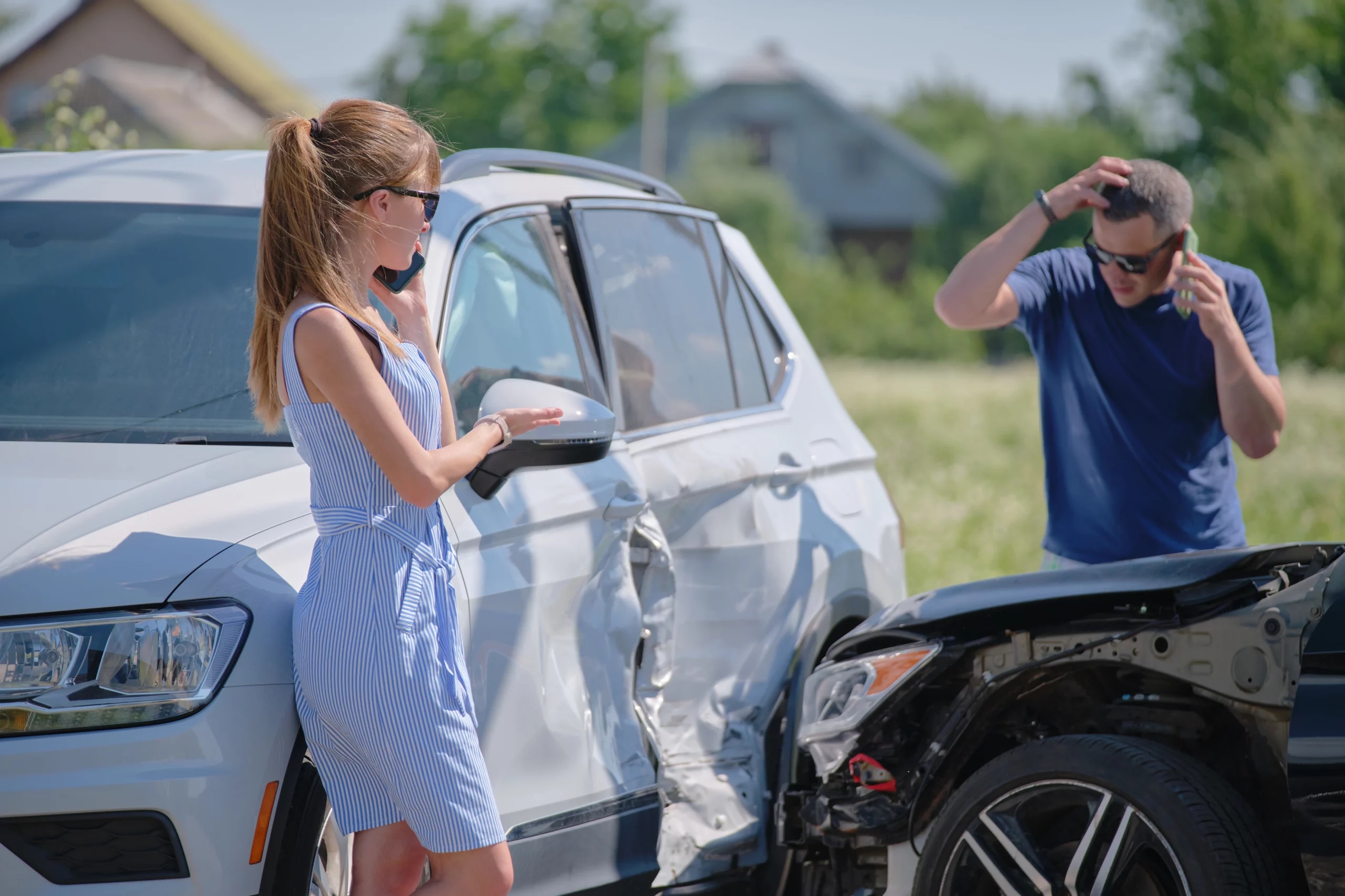 Woman in striped dress by damaged white car talking on phone